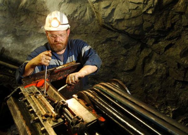 miner adjusting machinery with tools underground